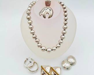 Sterling Silver Native American Style + Mexican Jewelry! A wonderful group of vintage sterling silver jewelry including a wonderful set of handmade silver Mexican Navajo "pearls" necklace measuring 18 inches long, the beads graduating from 6 mm to 15 mm; a signed J C Delgarito sterling silver bear-shaped pendant; a pair of sterling silver Native American style hoop pierced earrings; a pair of stamped sterling silver disc shaped Native style clip on earrings; and a pair of sterling silver and brass Mexican clip on earrings