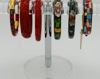 Carved rich red cinnabar bangle bracelets, a vintage Eisenberg Artist Series enamel bangle bracelet with a mosaic design and safety chain, and vintage fashion painted and cloisonné bangle bracelets