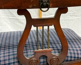 Closeup of the Duncan Phyfe-style mahogany lyre-back chair with lion head pull, seat with plaid upholstery