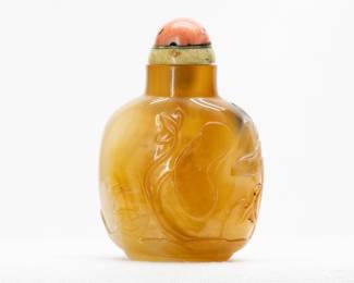 Another view of the Chinese Carved Agate Snuff Bottle: Stunning Chinese hard stone snuff bottle of compressed bulbous form with a concave lip and recessed foot, carved to display a pair of ducks swimming amidst lotus plants, with a lone monkey perched on a stylized rock, holding a peach in its upraised paw; jade and coral stopper.