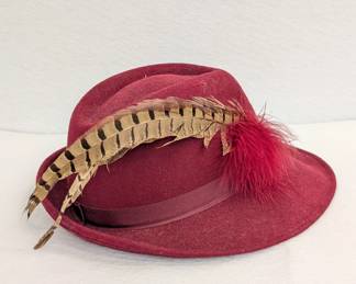 A vintage burgundy wool fedora hat with pheasant feathers