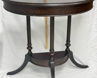 A vintage Bombay Company half-round side table with a dark finish and golden decorative accents. 