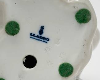 Closeup of Lladro porcelain figurine of a seated girl in Pierrot costume, leaning on an accordion while she reads a book