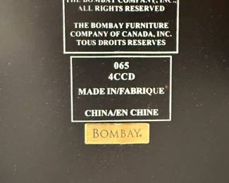 Closeup of underside of the vintage Bombay Company half-round side table with a dark finish and golden decorative accents. 