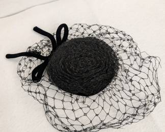A vintage black pillbox hat with netting and velvet bow
