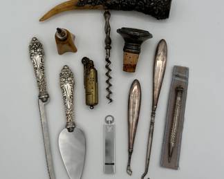 Antique sterling silver handle cheese knife and cheese server, sterling silver button hooks, a Bakelite lighter, a limited edition Louis Vuitton Cup 2000 silver whistle pendant, and a rare vintage Bowers "Sure-Fire" trench lighter, also known as a Kalamazoo lighter. These lighters were popular with soldiers during and after WWI and WWII due to their durable, windproof design.