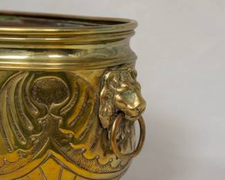 Another view of the antique oval brass and copper jardiniere or cachepot with two lion head ring handles and standing on paw feet