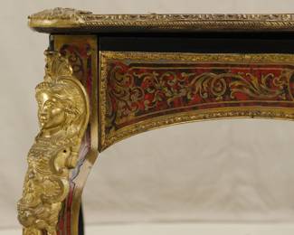 Closeup of the Napoleon III Boulle Inlay Bureau de Plat, 3rd quarter of the 19th Century. Crafted in the style of Louis XV with cabriole legs adorned with female allegorical figures, the red tortoiseshell top meticulously inlaid with brass depicting Diana the Huntress riding her chariot amidst scrolls and floral details. A large single drawer with a shield at center, and with a custom carved glass top.