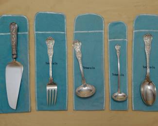 Tiffany sterling silver serving pieces in the Olympian pattern, each with Tiffany storage bag. A cake server, serving fork, two ladles, and large serving spoon each in the incredible multi-motif Olympian pattern, which was introduced by Tiffany & Co. in 1878. The Olympian pattern is the most elaborate and complex of all Tiffany flatware designs – each piece of Olympian is designed to illustrate a well-known story of Classical mythology; the subjects vary on the different pieces. Marked with Tiffany & Co Sterling.