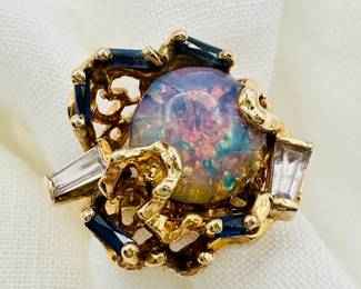 Closeup of the vintage gold ring set with large black opal flanked by two baguette cut diamonds and faceted sapphire blue stones; ring is size 8-1/4.