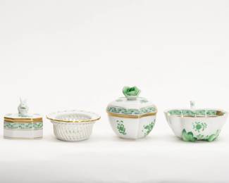 A group of four items from Herend Porcelain hand painted in the Chinese Bouquet pattern, green, comprising of covered heart-shaped box with rose finial (3 inches L x 2-1/2 inches H), a leaf shaped dish with handle (4-1/2 inches L x 3 inches W x 1 inches H), a Small Bunny octagonal trinket box (2 inches L x 2 inches W x 2 inches H), and an oval bowl with openwork woven gallery (4 inches L x 2-1/2 inches W x 1 inches H). The Herend mark on the base of each item. Founded in 1826, the Herend Porcelain Manufactory in Hungary continues to produce a wide variety of high quality hand painted porcelain sets and ornamental pieces.