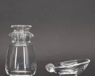 A mid-century-modern signed Steuben clear glass cocktail shaker No. 7894 from their “teardrop" series designed by Donald Russell. The body with double pour spouts and the stopper containing a teardrop bubble are signed with etched Steuben signature.   Designed in 1941, manufactured 1941–1950. Examples of this MCM Steuben cocktail shaker can be seen in the Chrysler Museum of Art and the Brooklyn Museum. Shown with a signed Steuben crystal glass ashtray in the "Sloping Bowl" or "8028 Slope" design.