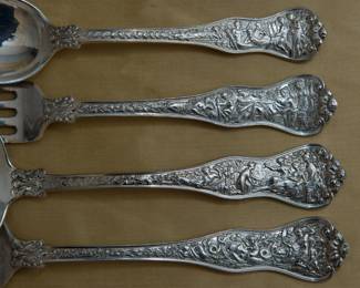 Closer view of the Tiffany sterling silver serving pieces in the Olympian pattern, each with Tiffany storage bag. A cake server, serving fork, two ladles, and large serving spoon each in the incredible multi-motif Olympian pattern introduced by Tiffany & Co. in 1878. Marked with Tiffany & Co Sterling. The Olympian pattern is the most elaborate and complex of all Tiffany flatware designs – each piece of Olympian is designed to illustrate a well-known story of Classical mythology; the subjects vary on the different pieces. Scenes shown in this photo include the Judgement of Paris, and Venus Born on the Sea.