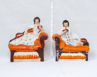 A pair of vintage Staffordshire flat back bookends or mantel figurines, of a man and woman each reclining on a chaise longue with a musical instrument while reading a book