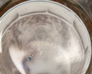 Closeup of base of the antique 1920-30s Moser crystal perfume bottle with atomizer top and etch metal band of Amazon warriors around the fluted body