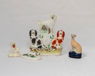 Three different Staffordshire dog figurines, and an antique English Staffordshire pottery figurine of a clock group featuring a poodle and two spaniels, mid-19th century