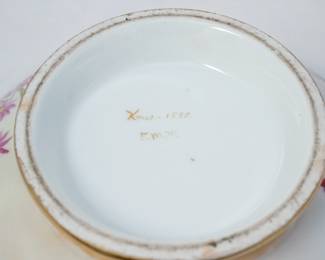 Closeup of the lovely porcelain bowl circa 1898, hand-painted with flowers over a shaded pastel background with gilded scrolls at the rim with an acanthus scroll cartouche containing initials. Signed on the base with "Xmas 1898 E. M. W."   
