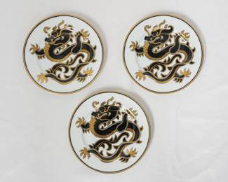 A set of three Fitz and Floyd "Ching Dragon" porcelain plates crafted in Japan featuring a black and gold imperial dragon design