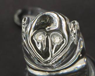 Closeup of Steuben Glass Mink Figurine with Diamond Inset Eyes. This inquisitive clear glass Mink is shape No. 8334 from Steuben’s menagerie of charming animal figures, and has the special touch of inset diamond eyes. Designed by Lloyd Atkins and introduced in 1976. Etched Steuben signature on bottom and stands 7-1/2 inches H. 