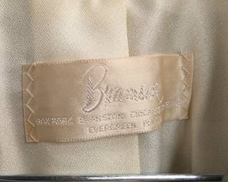 Closeup of vintage Bramson's Chicago 50s/60s light grey wool skirt suit with straight skirt and a 3/4 length sleeve short waisted jacket with accent belt