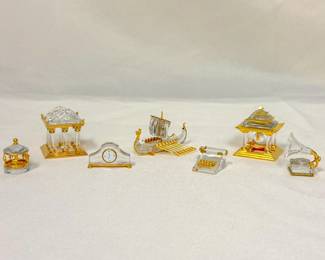 A selection of Swarovski Crystal figurines crafted of sparkling crystal and gold-plated accents: Merry Go Round Carousel, Greek Temple, Mantel Clock, Viking Ship, Typewriter, Japanese Temple, and Gramophone.