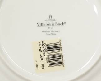 Closeup of the base of a piece from the fine Villeroy & Boch porcelain dinnerware in their country style pattern Audun Ferme, showing pastoral scenes in dark gray and white with a distinctive yellow accent border. Four dinner plates, four salad plates, four soup/cereal bowls, along with four flat cup and saucers, four coffee mugs
