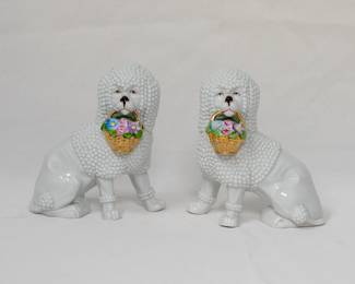 A vintage pair of ceramic poodle dog figurines, each holding the handle of a basket of flowers in its mouth; clear glaze and polychrome enamels. Possibly German made, late 19th/early 20th century