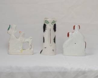 Another view of the antique Staffordshire flat back ceramic spill vase modeled as a dog next to his doghouse, looking up at a bird resting on a tree trunk; a 19th century Staffordshire King Charles spaniel jug, the dog sitting up in begging position and wearing a hat in the "Toby Jug" style; and a Staffordshire flatback figurine of two King Charles Spaniels, one perched on a barrel. The flat back figures were usually placed on fireplace mantels.