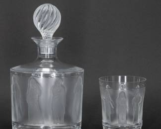 A Lalique crystal decanter with a stopper and one tumbler or whisky glass, in the Femmes Antiques pattern originally designed by Marc Lalique in 1952. Clear and satin finish glass, molded with classical figures, and engraved signature Lalique France in script on the base. Decanter 9 1/2 inches tall, tumbler is 4 inches tall.