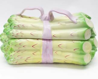 From the Herend Porcelain Manufactory in Hungary, a hand painted porcelain trinket box in the form of a bundle of asparagus tied with a pink ribbon. The interior is white glazed porcelain and has a manufacturer's mark on the inside. 5 1/2 inches L x 3 inches W x 3 inches H.