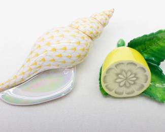 Two hand painted porcelain pieces comprising one Herend Tulip Shell in butterscotch fishnet pattern, and a Herend Lemon on Leaf menu or place card holder. Each with the Herend manufacturer marks to the base. Measurements: Shell 5 inches L x 2 1/2 inches W x 1 inches H, lemon 3 inches L x 2 1/2 inches W x 1 1/2 inches H.