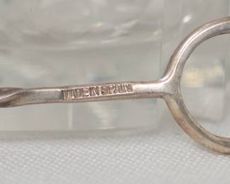 Closeup of the vintage glass condiment or jam dish with a silver handle for the hanging spoon, frame says Made in Spain. 