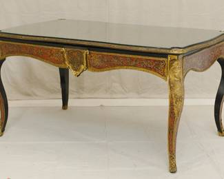 A Napoleon III Boulle Inlay Bureau de Plat, 3rd quarter of the 19th Century. Crafted in the style of Louis XV with cabriole legs adorned with female allegorical figures, the red tortoiseshell top meticulously inlaid with brass depicting Diana the Huntress riding her chariot amidst scrolls and floral details. A large single drawer with a shield at center, and with a custom carved glass top.