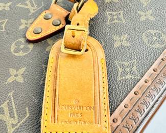 Closeup of the 1980s vintage Louis Vuitton monogram Boite Bouteilles train case, a hard-sided trunk case crafted of Louis Vuitton Monogram coated canvas with a vachetta leather top handle, reinforced brass corner plates, S lock and two latches. The top opens to a beige leather interior with a full mirror set in the lid, vachetta leather belts for bottles, and a removable tray insert. Comes with a dust bag, name tag, and keys. Certificate of authenticity from Entropy.