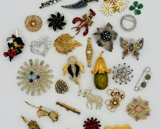 Fashion brooches galore including a Bakelite and gold tone squash blossom, some trembler brooches (lobster and a swooping swallow in flight), and a vintage Emmons "Kismet" starburst brooch with a textured gold-tone finish and multi-colored rhinestones