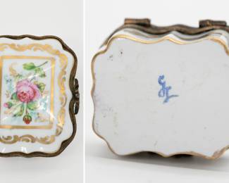 A vintage hand-painted Limoges porcelain trinket box with a brass hinge and a floral design of roses on the lid