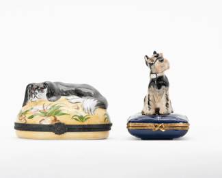 2 Limoges Boxes Dogs Schnauzer & Spaniel France Rochard – Limoges Box One: An inquisitive Schnauzer dog wearing a collar and seated on a square shaped blue cushion. Inside the box, a finely modeled dog bone. Marked to the base with Peint main Limoges France and Rochard Limoges Original. Limoges Box Two: An oval form box with yellow ground and plants, a King Charles Spaniel on the lid, curled up with its head on its paws, and a dog bone at its feet. Inside the box is a painted outline of a dog bone. Stamped LIMOGES FRANCE in green paint on the base, along with artisan’s mark.