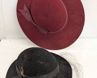 A vintage Fabini New York black wool felt hat with a wide brim, ribbon band and netting veil; and a vintage Doeskin Felt burgundy wool hat with wide brim and ribbon band