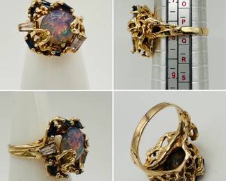 A vintage gold ring set with large black opal flanked by two baguette cut diamonds and faceted sapphire blue stones; ring is size 8-1/4.