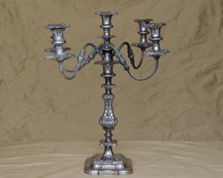 An exquisite antique silver plated five-light candelabra featuring four gracefully extending S-scroll arms adorned with applied stipple and chased leaf motifs, culminating in foliate repoussé drip pans and baluster-shaped candle cups with matching foliate-chased bobeches. The central candle cup mirrors this elaborate design, crowning the highly ornamented standard. The five-light section is removable, so that the baluster form base, richly embellished with foliate scrollwork, can be used as a single candlestick. There is a maker's mark to the underside of the five-light section, where it fits into the base.