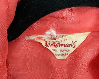 Closeup of vintage coral or reddish-orange color robe made in Japan, with floral pattern embroidery and white piping along the collar, cuffs, and pockets