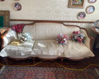 antique French Louis XV-style sofa with a carved wood frame and off-white upholstery.