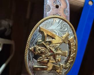 A and M belt buckle on a tooled leather belt.
