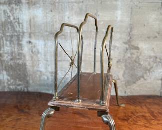 This lot features an Art Nouveau brass and wood magazine rack circa 1930s that measures, 18.5” H x 20.5” W x 12.5” D.
