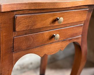 This lot features a Louis XV-style carved wooden nightstand with two drawers and cabriole legs in very good condition. This nightstand measures, 27.5” H x 17.5” W x 12.5” D.
