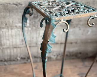 This lot features a vintage verdigris metal plant stand in good condition that measures, 25” H x 12.5” W x 12.5” D.
