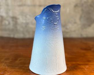 This lot features a Tschudy pottery cat vase pitcher in excellent overall condition, with maker mark underneath, and measures, 8” H x 5” W x 6” D. This ceramic vase has a cat face design with a blue and white ombre glaze.
