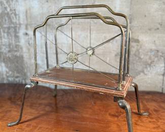 This lot features an Art Nouveau brass and wood magazine rack circa 1930s that measures, 18.5” H x 20.5” W x 12.5” D.
