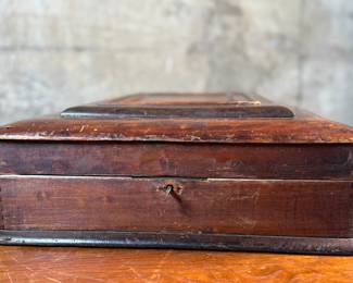 This lot features what appears to be a Victorian writing slope or lap desk. Locks and comes with the original skeleton key, with beautiful patina throughout. Please note, there is no "slope" and has a flat box surface inside. This stunning piece measures, 5” H x 14.5” W x 17.5” D.
