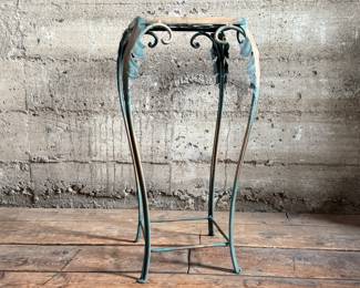 This lot features a vintage verdigris metal plant stand in good condition that measures, 25” H x 12.5” W x 12.5” D.
